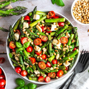 Asparagus Caprese Salad with roasted green asparagus, tomatoes and mozzarella in a bowl.
