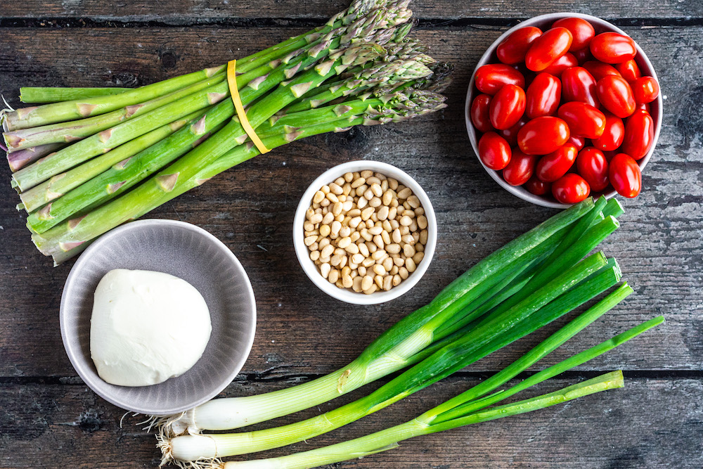 Main ingredients for the Asparagus Caprese Salad: Green asparagus, cherry tomatoes, pine nuts, mozzarella and scallions.