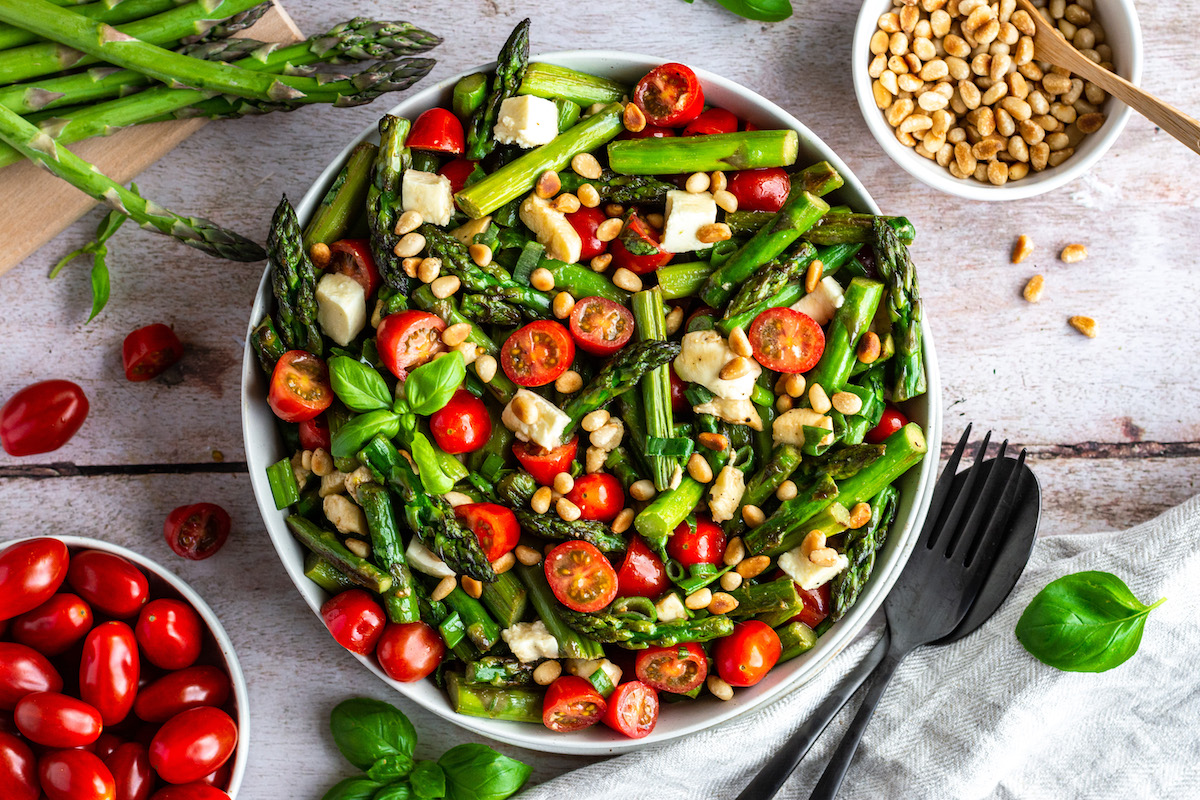 Asparagus Caprese Salad with roasted green asparagus, tomatoes and mozzarella in a bowl.