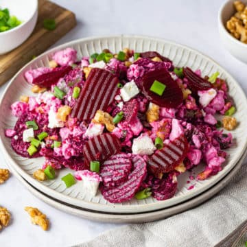 Beet Salad with pickled beet, feta cheese, walnuts and green onions on a white plate.