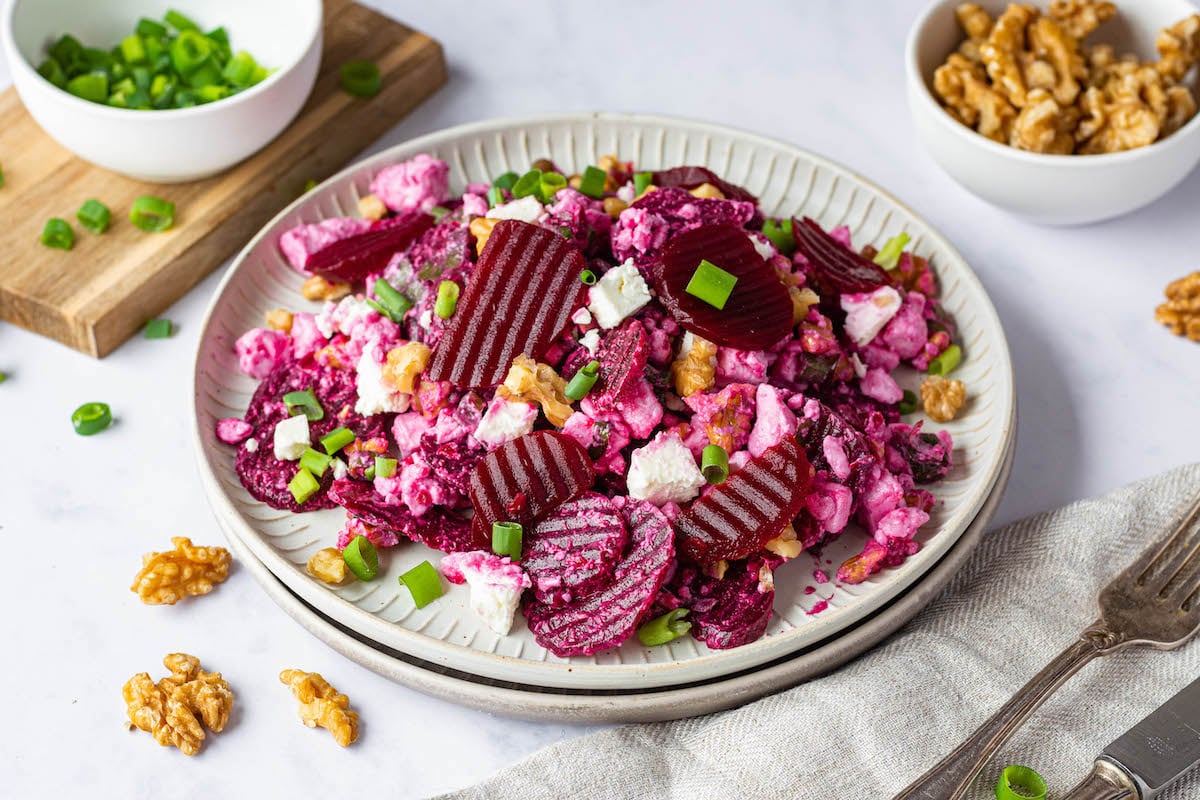 Beet Salad with pickled beet, feta cheese, walnuts and green onions on a white plate.