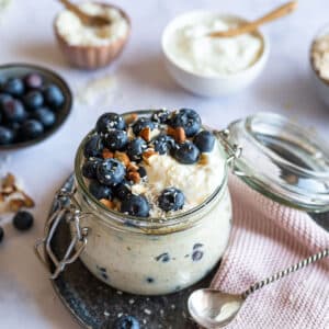 Blueberry Overnight Oats with Greek Yogurt and coconut flakes in a glass jar.