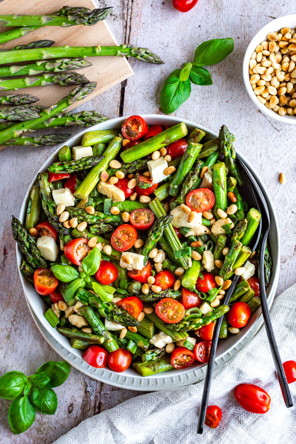 Caprese Asparagus Salad in a bowl with black knive and fork.