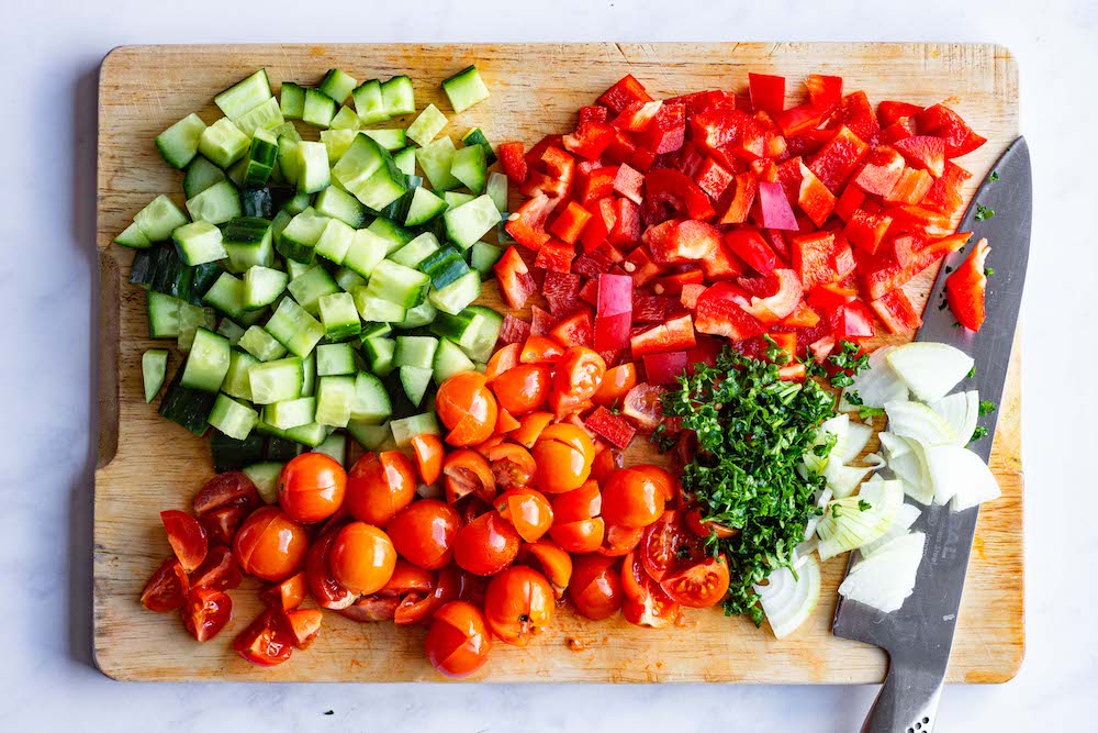 Chopped up cucumber, tomatoes, bell pepper, parsley, and onions.