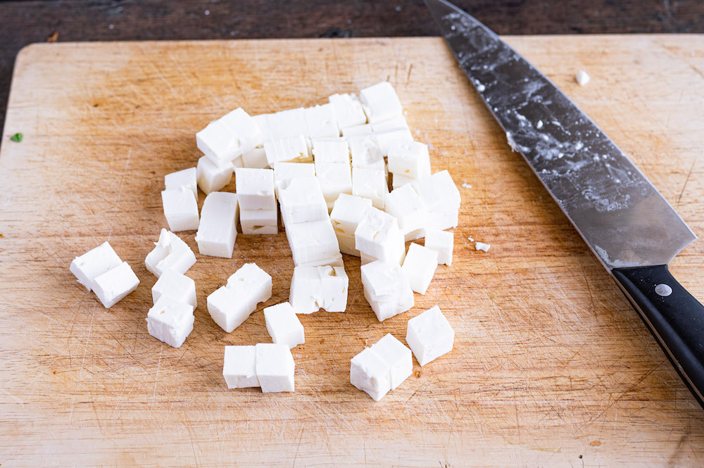 Cutting feta cheese into small chunks.
