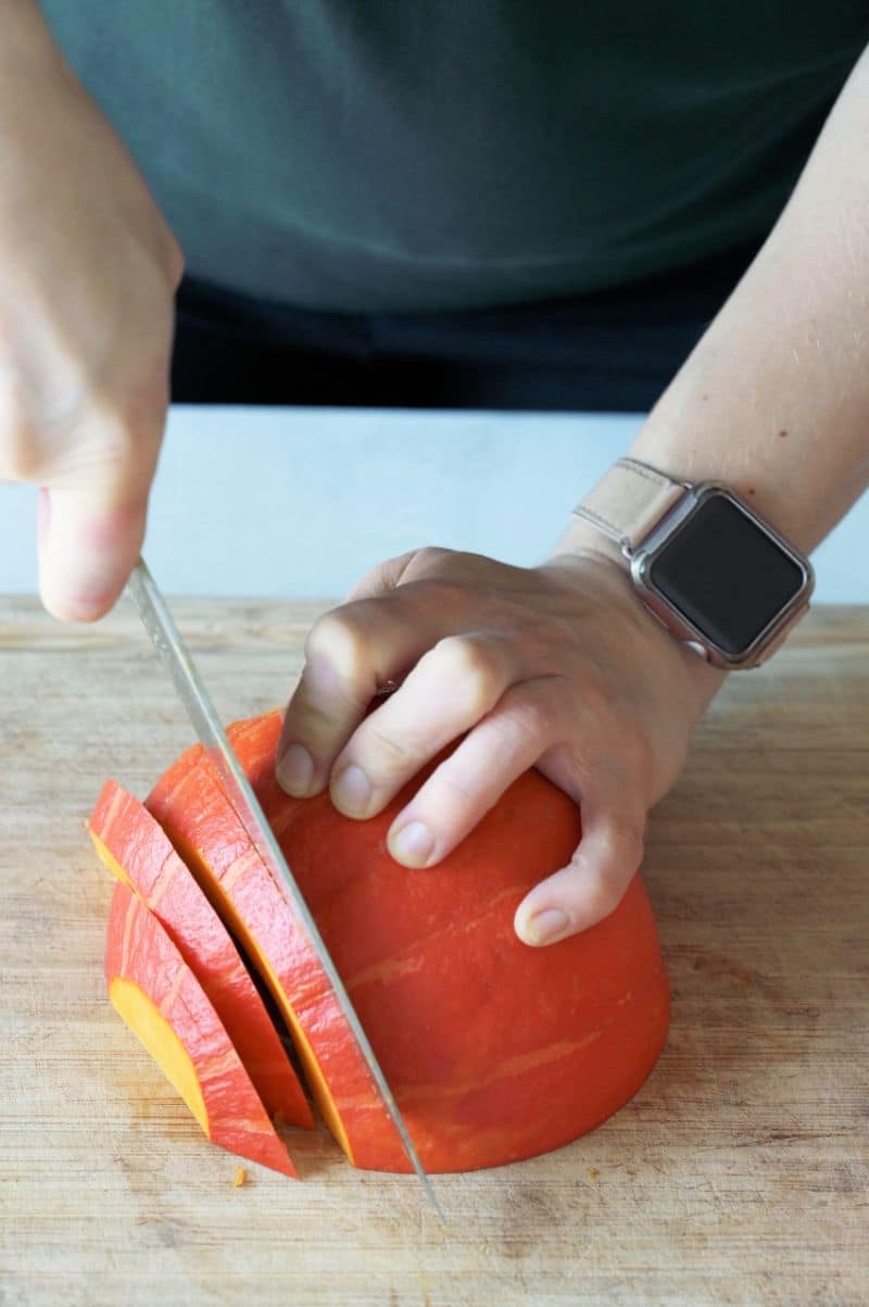 A kabocha squash half is being cut into wedges.