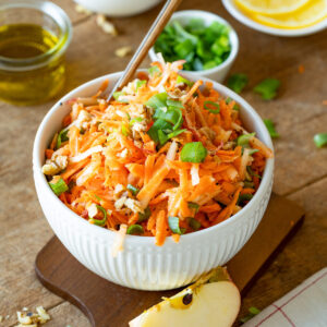 German Carrot Apple Salad with Walnuts and Scallions in a white bowl.