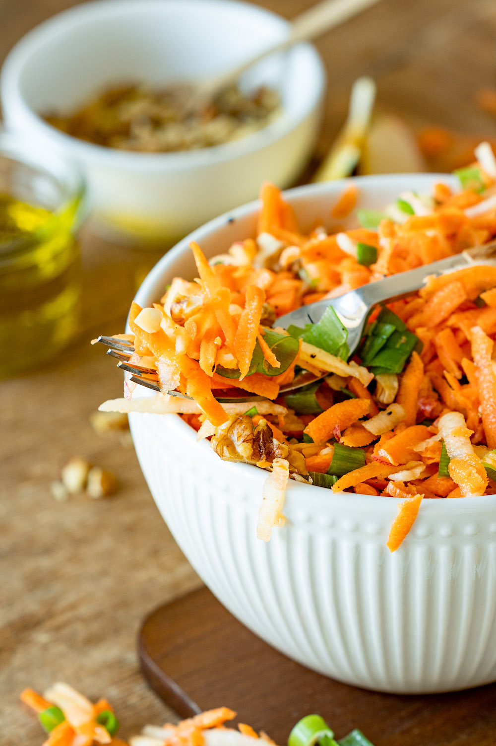 Close up of a German carrot salad with apple, walnuts and spring onions.