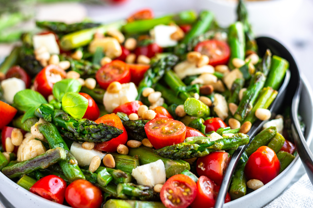 Close-up of asparagus caprese salad with tomatoes and mozzarella in a bowl.