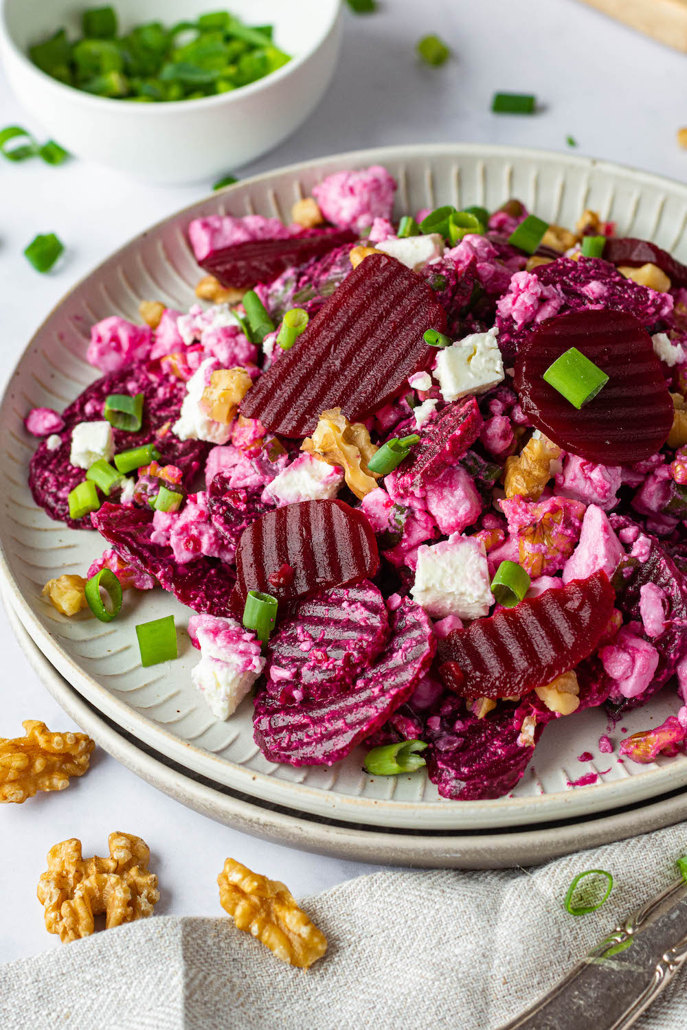 Beet Salad with pickled beet, feta cheese, walnuts and green onions on a white plate.