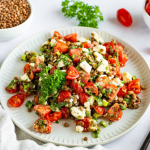 Lentil Salad with canned lentils, feta cheese and tomatoes on a white plate.