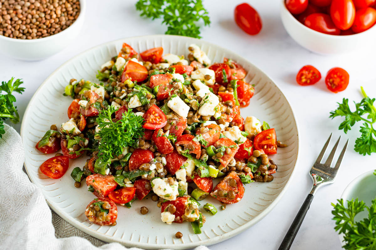 Lentil salad with feta and tomatoes on a white plate.