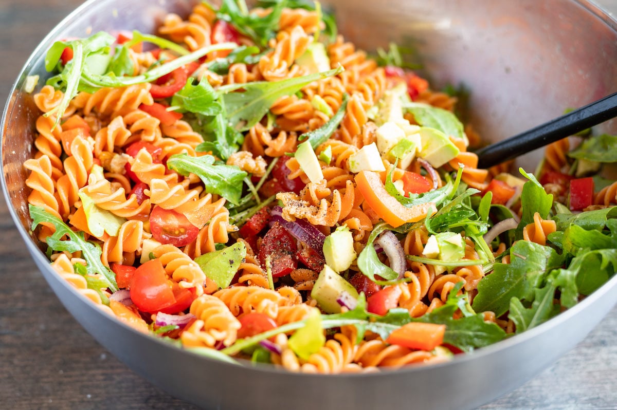 All ingredients for the red lentil pasta salad are mixed in a bowl.