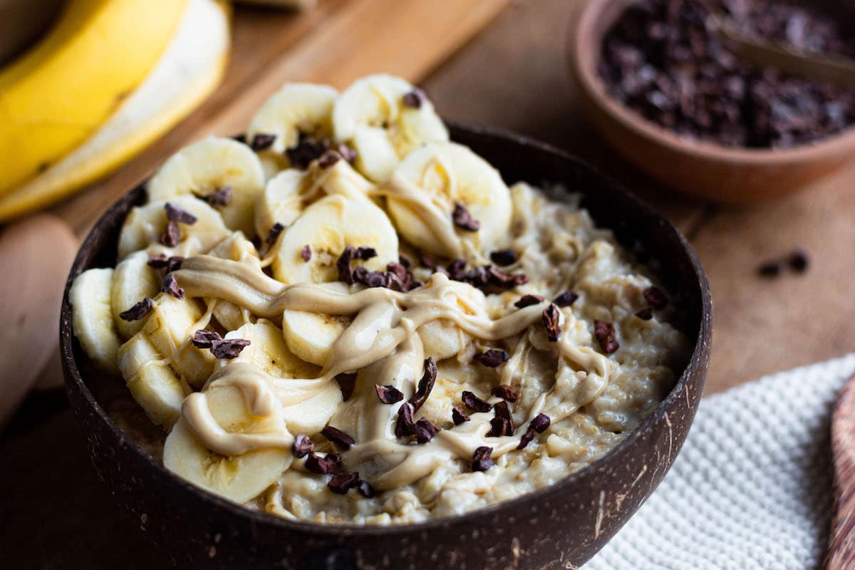 Oatmeal with banana and cashew nut butter Creamy oatmeal with mashed banana and cashew nut butter served in a bowl and topped with banana slices, cashew nut butter and cacao nibs.