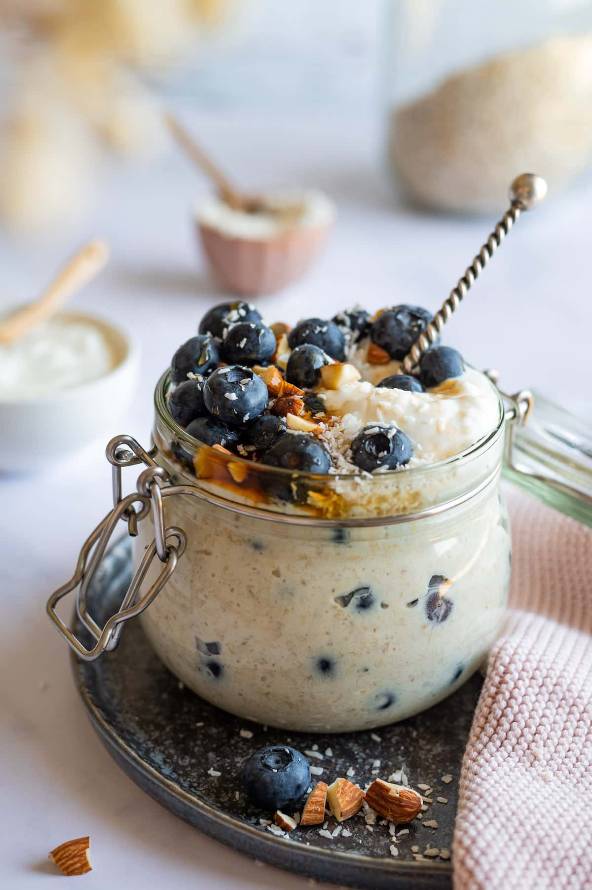 Overnight oats with blueberries, greek yogurt and coconut flakes in a glass jar.