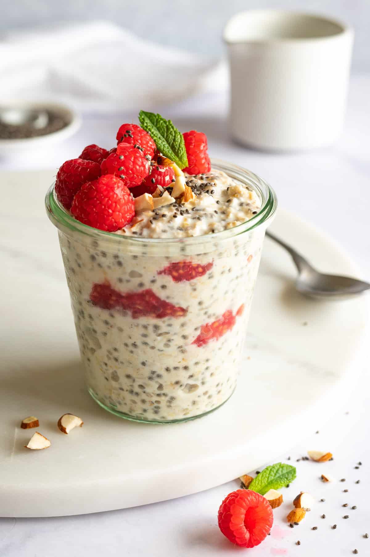Overnight oats with fresh raspberries, coconut and chia seeds in a glass jar. Decorated with fresh raspberries and mint.