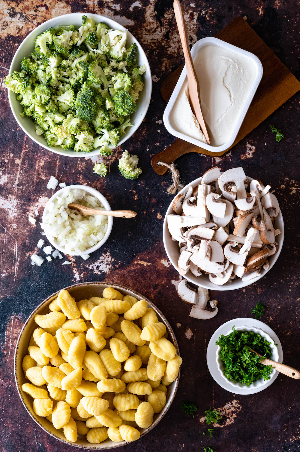 Overhead shot of ingredients for the pan-fried gnocchi: Skillet gnocchi, broccoli, mushrooms, parsley, onions and cream cheese.