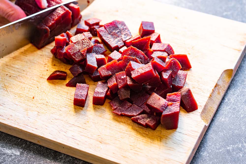 Cooked beetroot being cut into pieces.