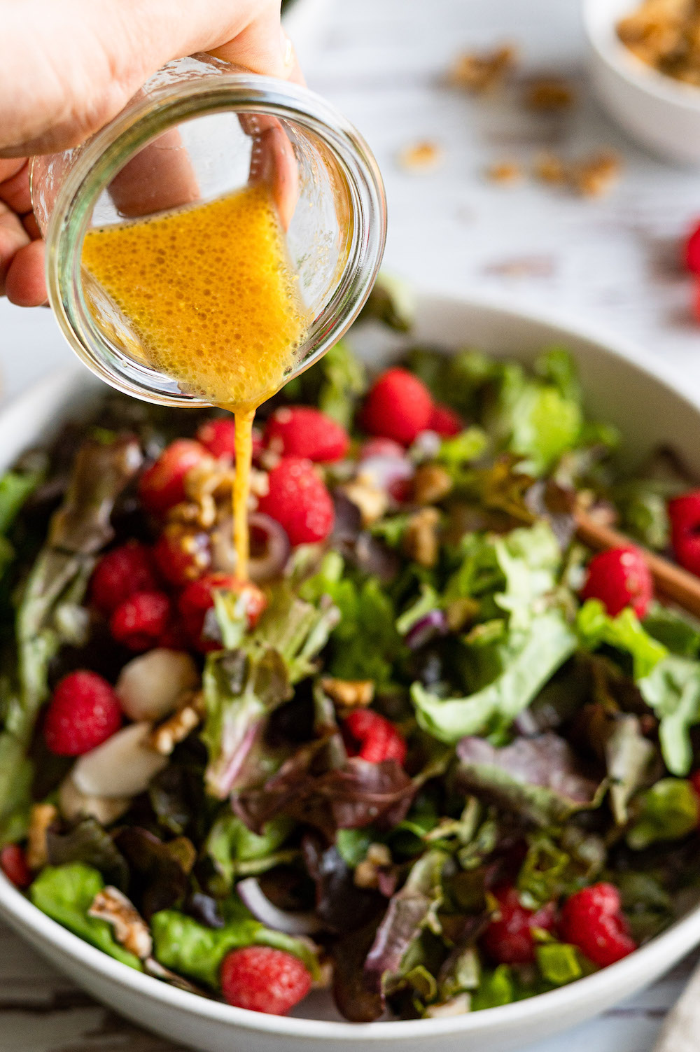 Raspberry vinaigrette (dressing) being poured over the rasperry salad.