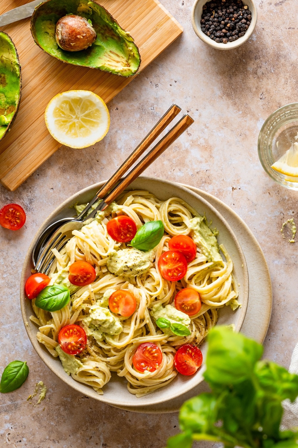 Quick and healthy avocado tomato pasta garnished with basil leaves.