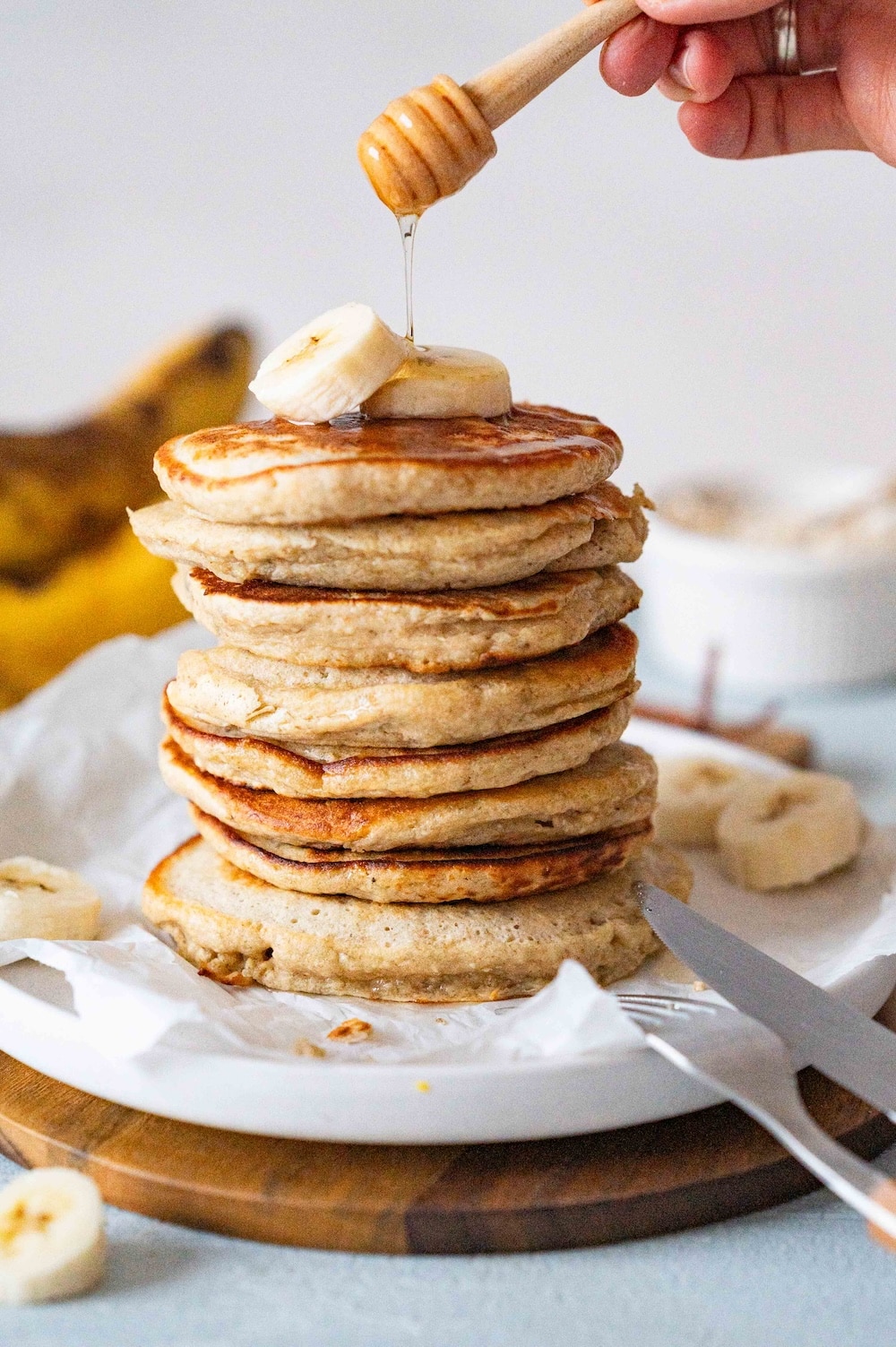 Sirup is being poured over a stack of healthy banana oatmeal pancakes.