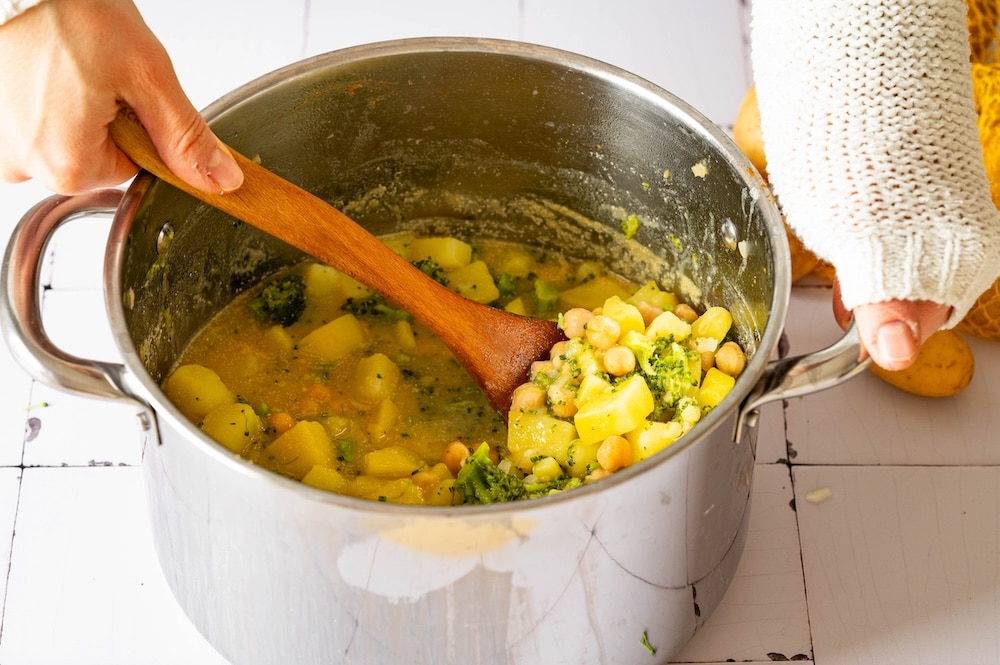 broccoli potato curry being stirred in a pot