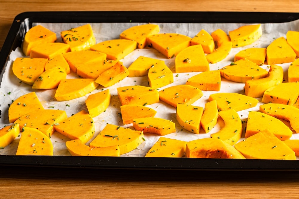 Butternut squash spread out on a baking sheet.