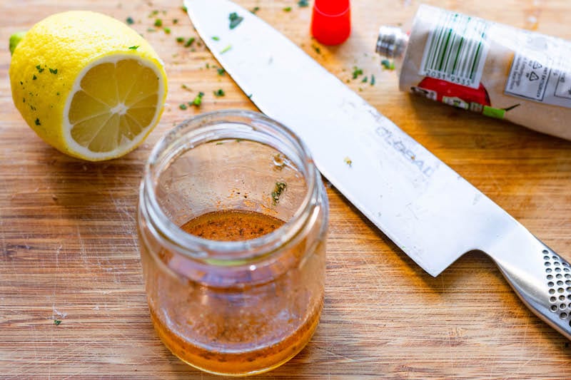 Dressing with tomato paste and fresh lemon juice combined in a glass jar.