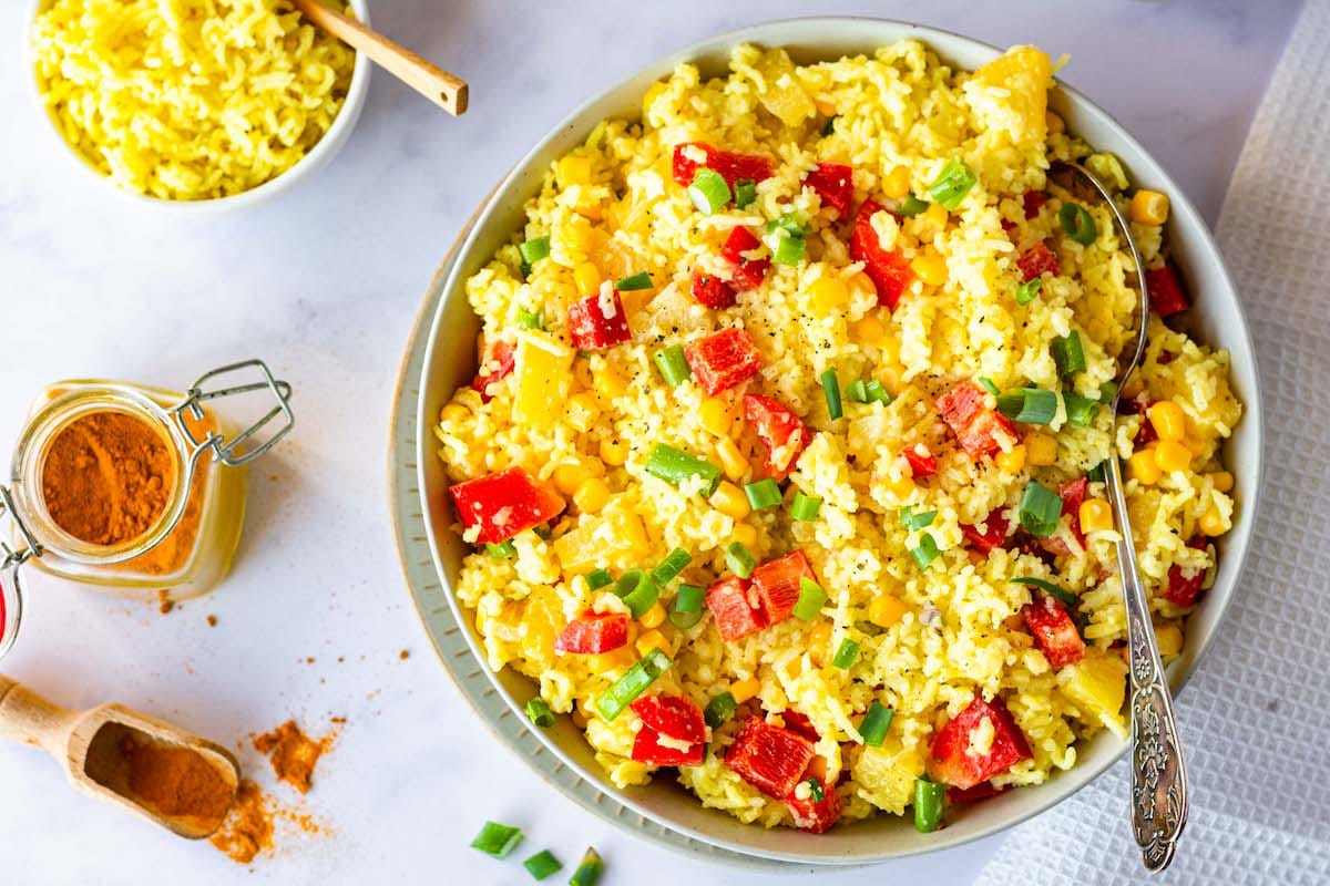 Curried rice salad with pineapple and yogurt dressing in a bowl with a spoon.