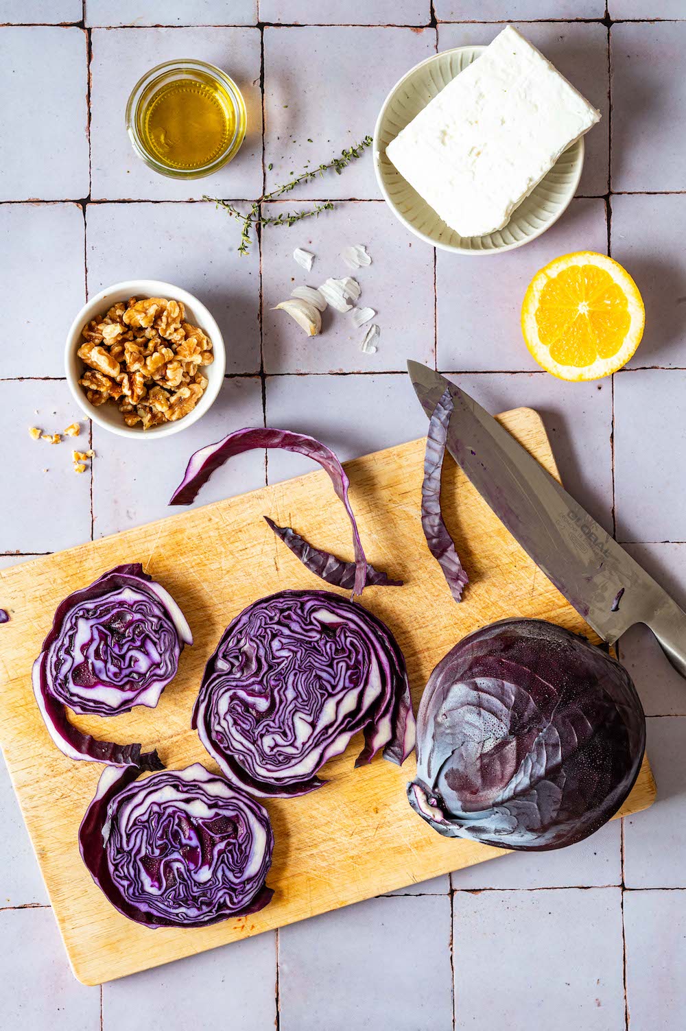 Overhead shot of ingredients: Red cabbage, walnuts, feta cheese, orange and olive oil.