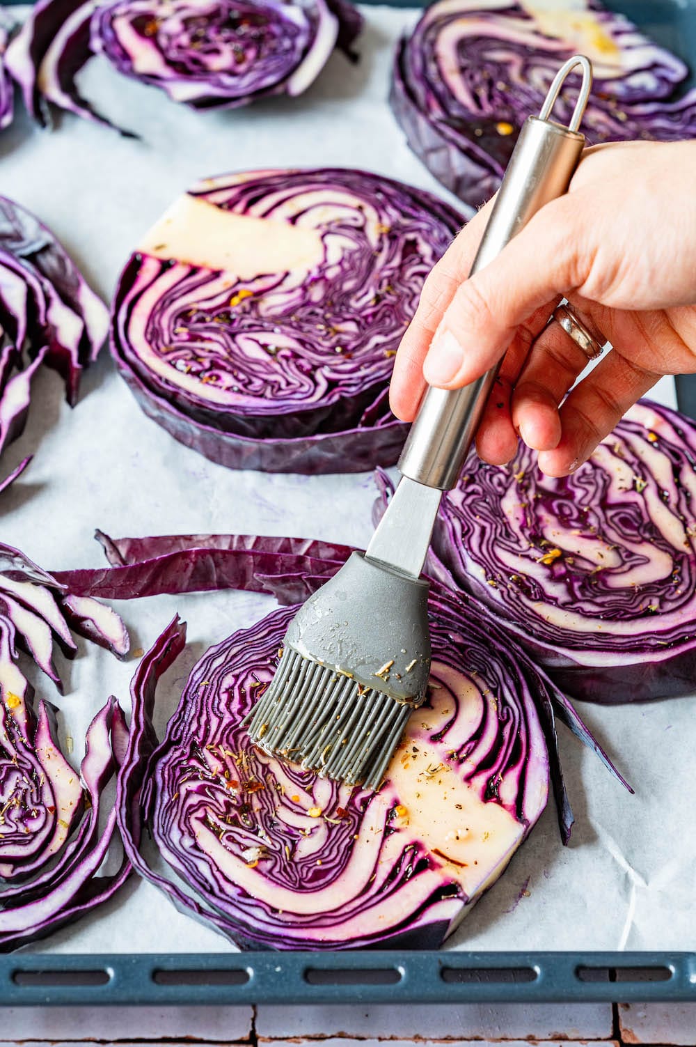 Slices of red cabbage are being coated with marinade.