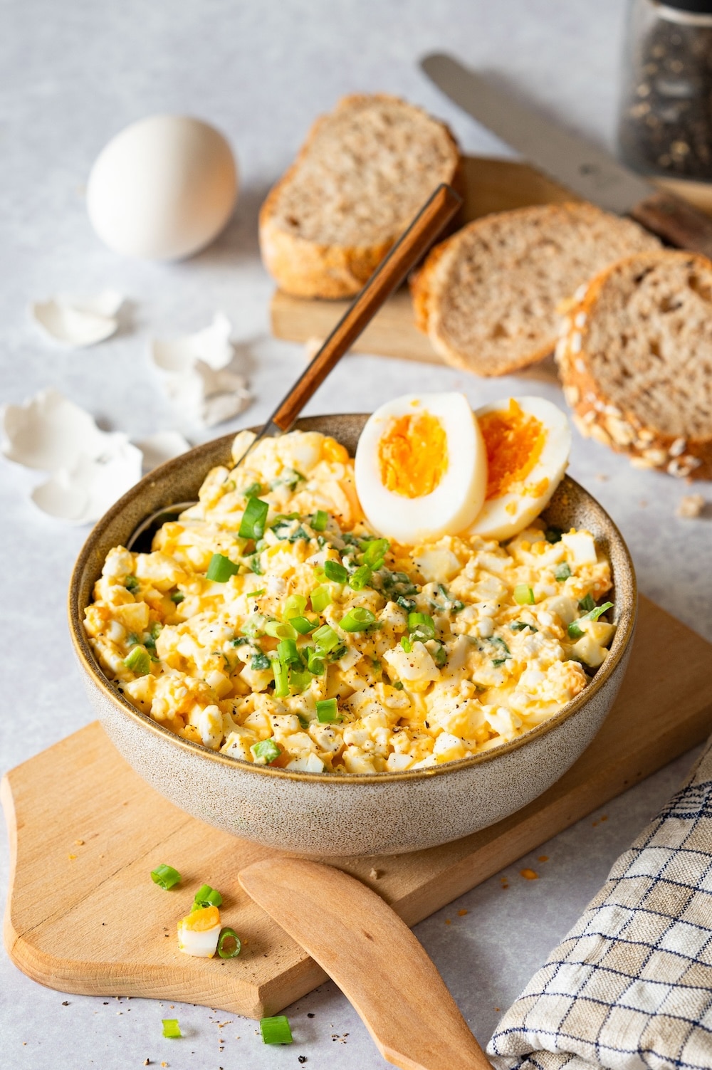 Protein egg salad with cottage cheese in a bowl, decorated with scallions and egg halves.