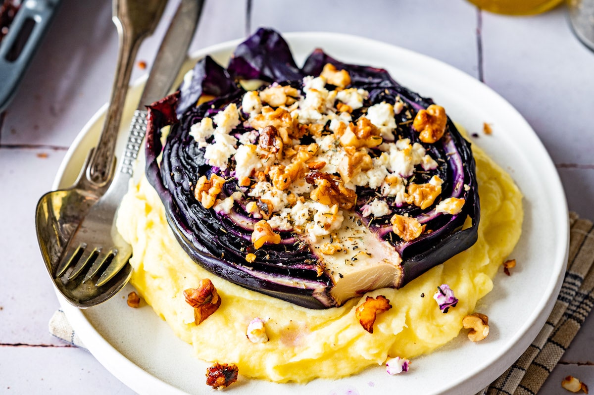 Roasted red cabbage steaks with feta and walnuts served with mashed potatoes.