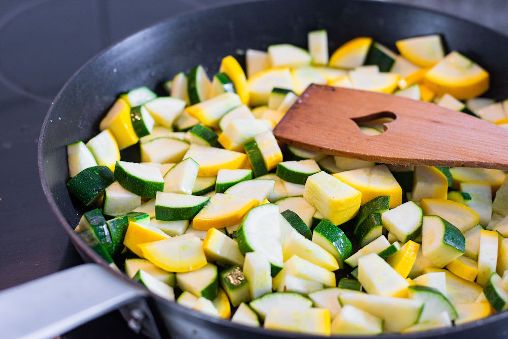 Zucchini chunks are being roasted in a skillet.