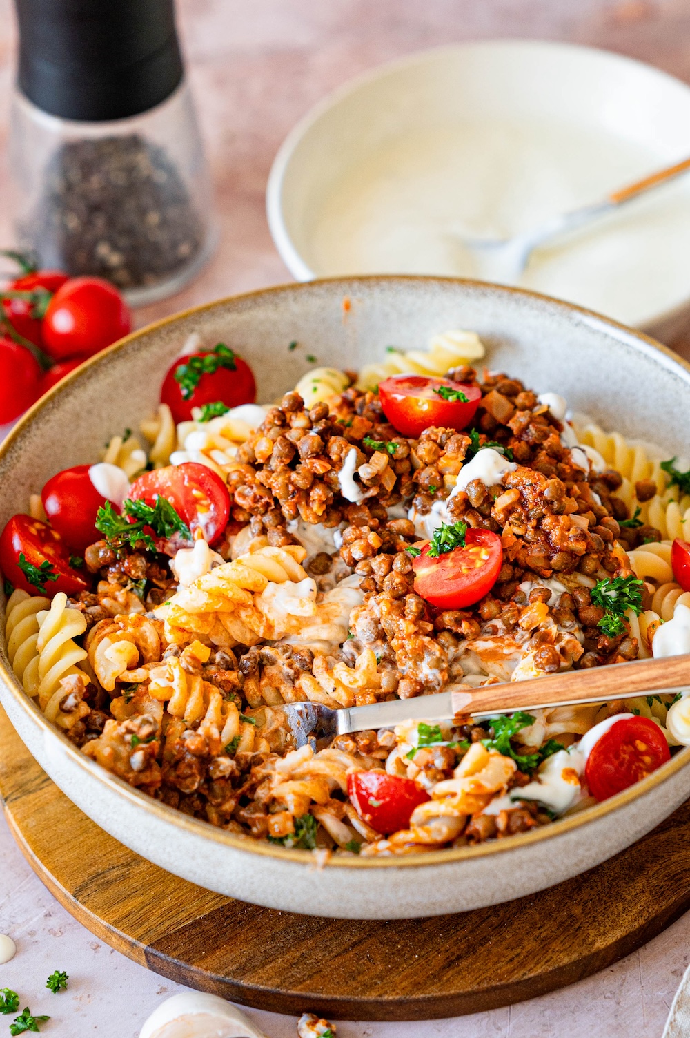 Vegetarian Turkish Pasta with lentils, tomatoes, yogurt, paprika-butter, and parsley mixed in a bowl.