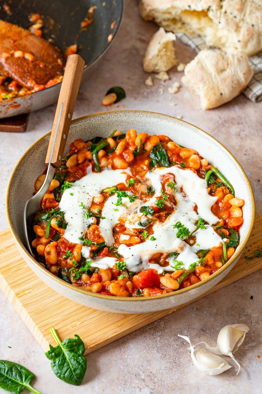 White Bean Curry with spinach and tomatoes, garnished with Greek yogurt and parsley.
